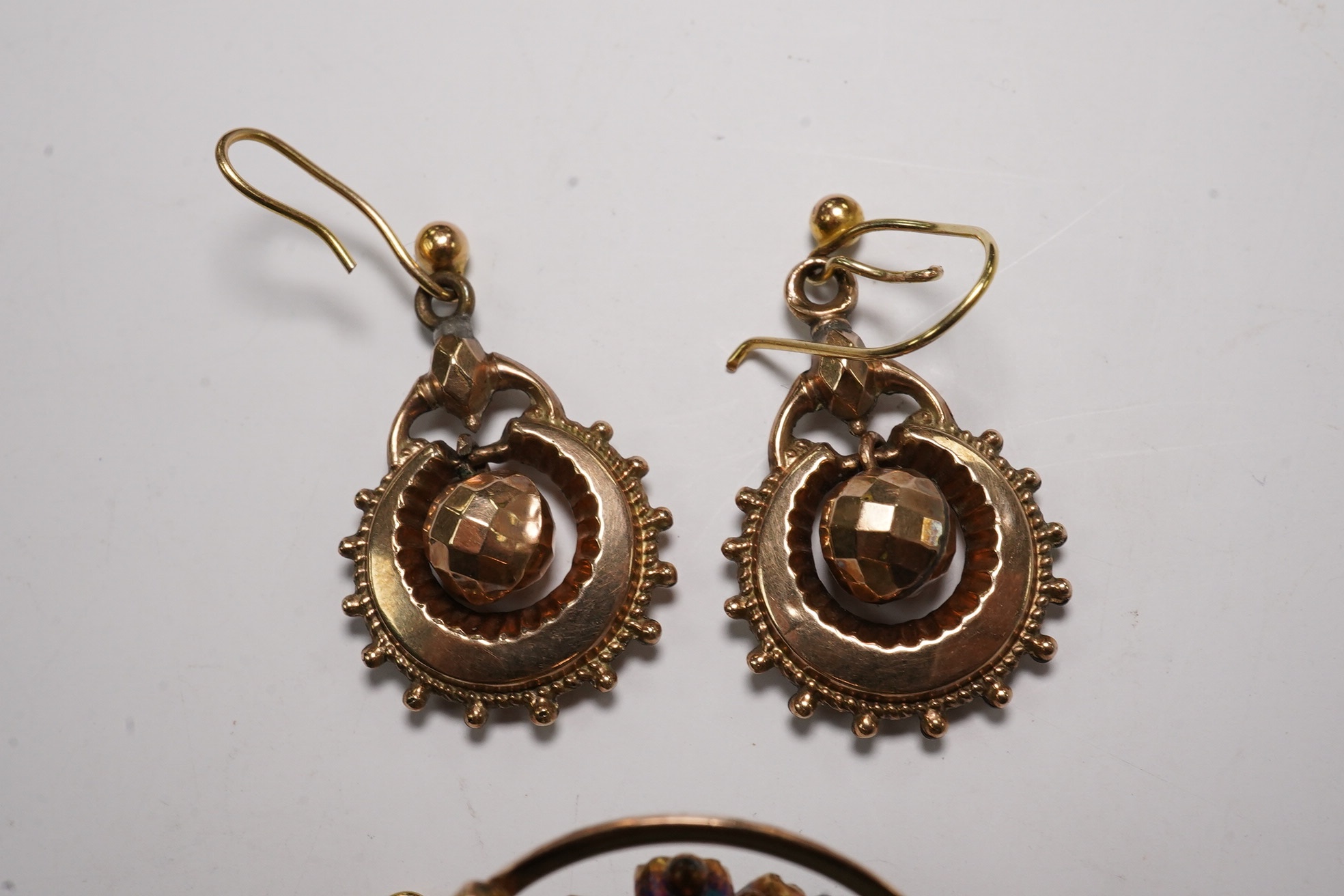 A pair of antique yellow metal drop earrings, 22mm and a yellow metal and two colour green gem set brooch. Condition - poor to fair